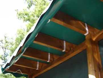 La fixation de la bache est completée par des rubans attachés aux solives