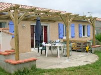 Pergola adossée sur une façade crépissée de couleur rose clair